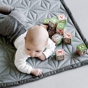 Baby playing on mint colour quilt