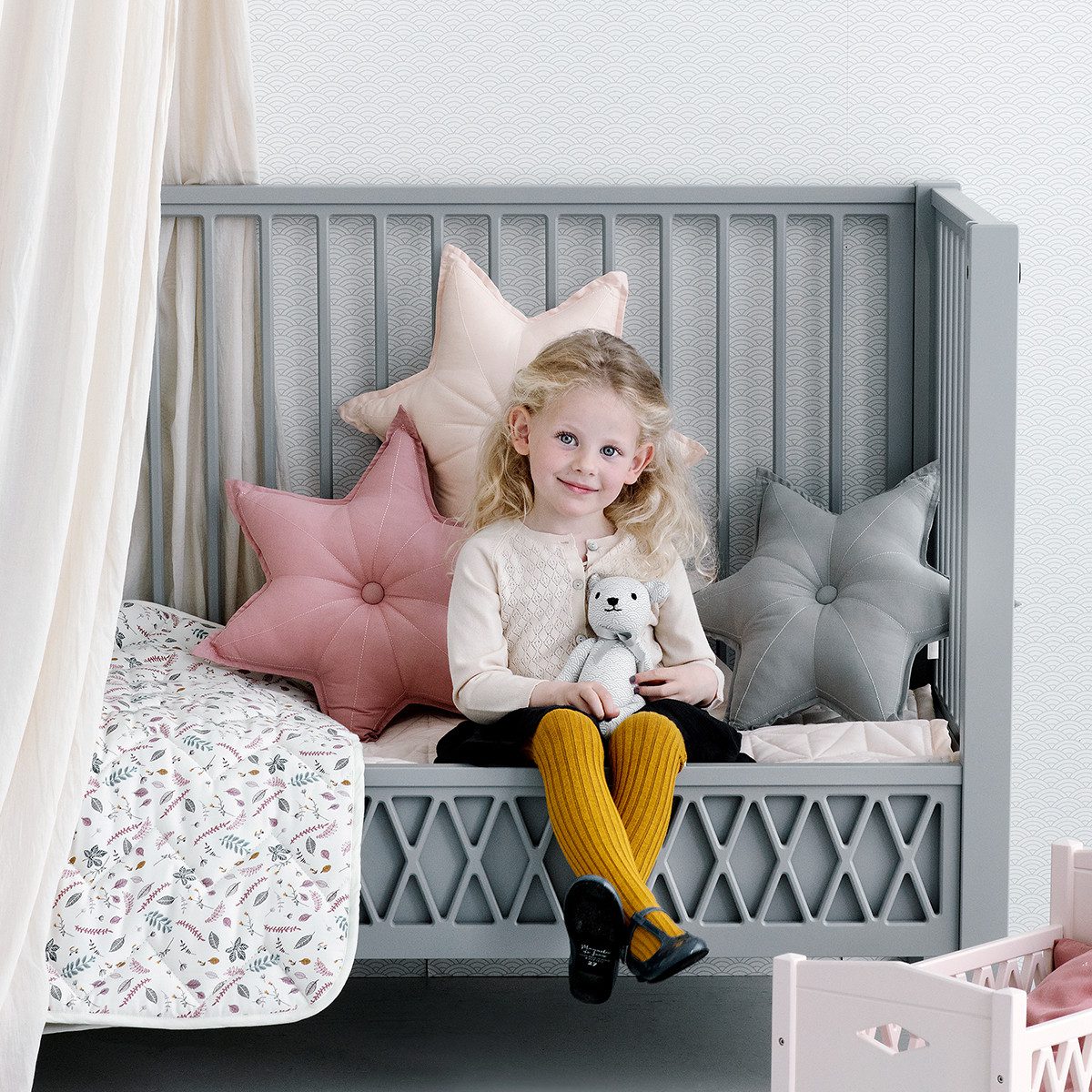 Child in nursery featuring star shaped cushion in old rose