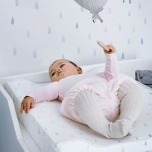 Baby laying on changing cushion in raindrops pattern