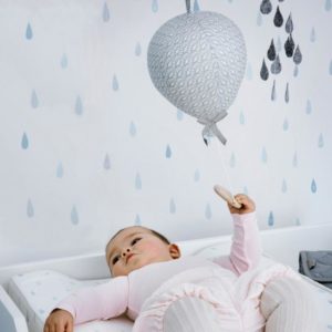 Baby with balloon music mobile in peacock grey on changing table