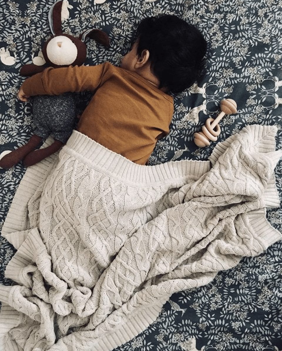 Child in nursery with wool knots blanket in sand