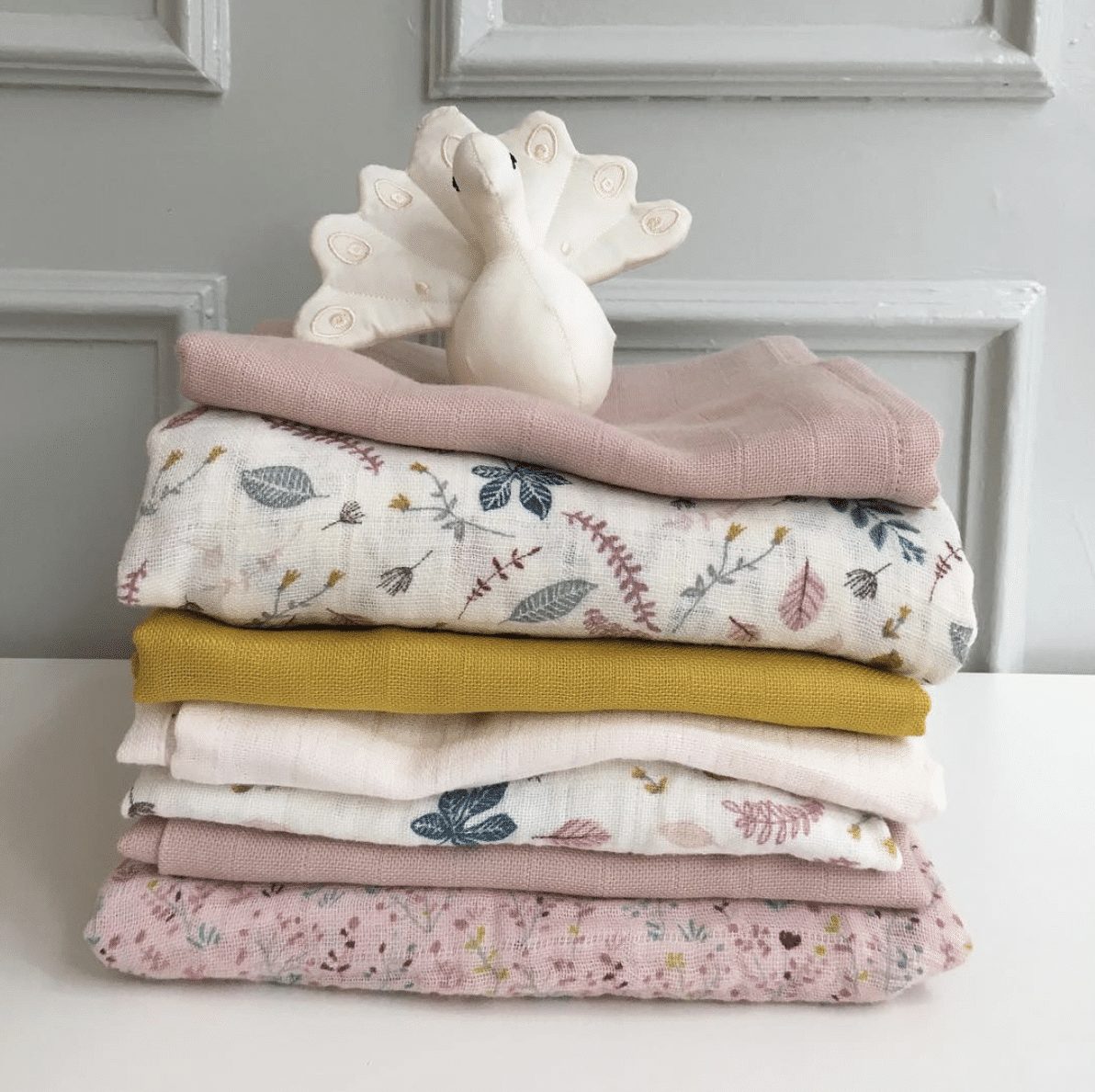 Stack of organic baby muslin wraps in prints and colours by Cam Cam