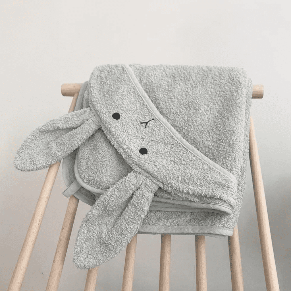 Dusty mint hooded baby towel folded on nursery chair