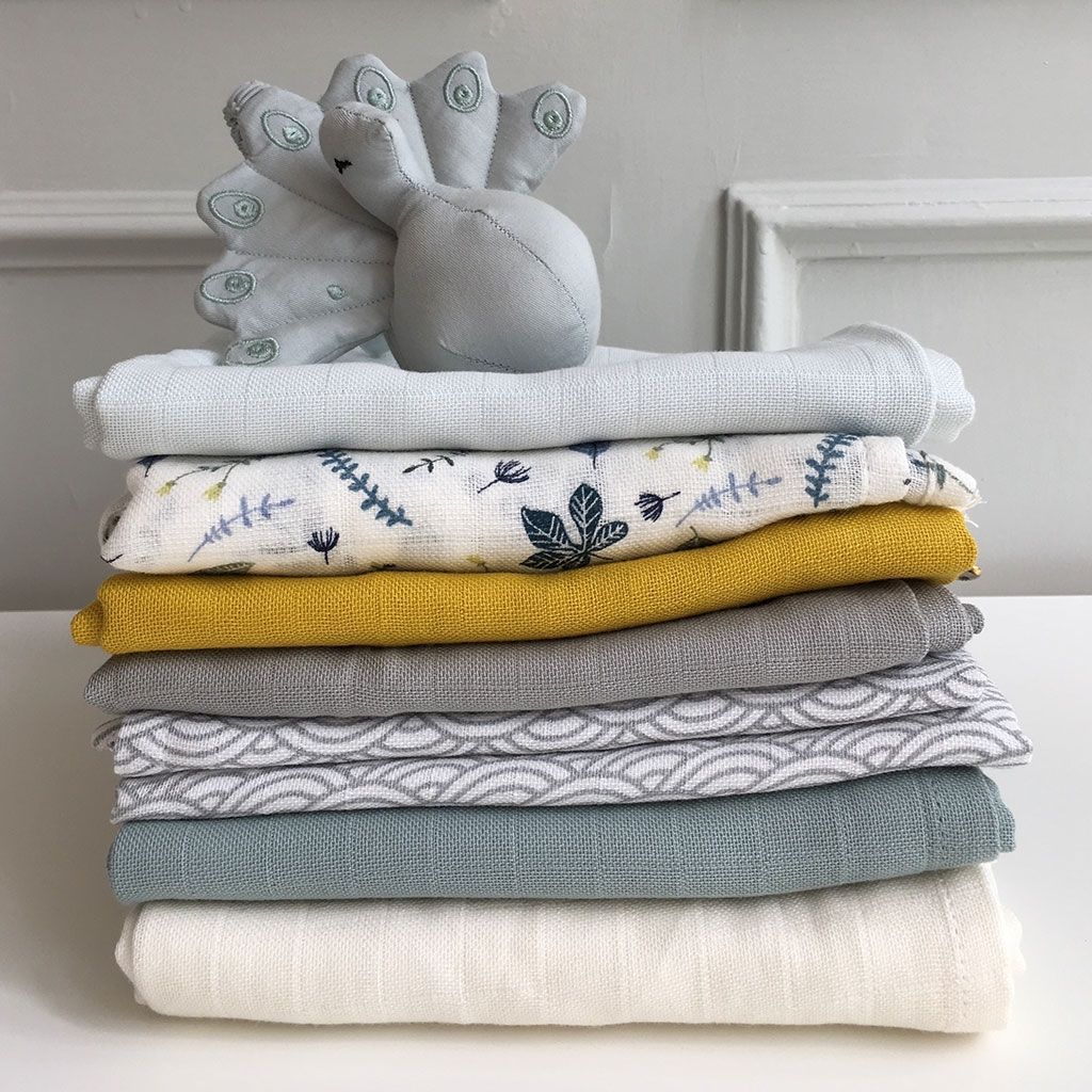Pile of organic cotton muslins wraps and swaddles in mustard, grey, petroleum and other colours