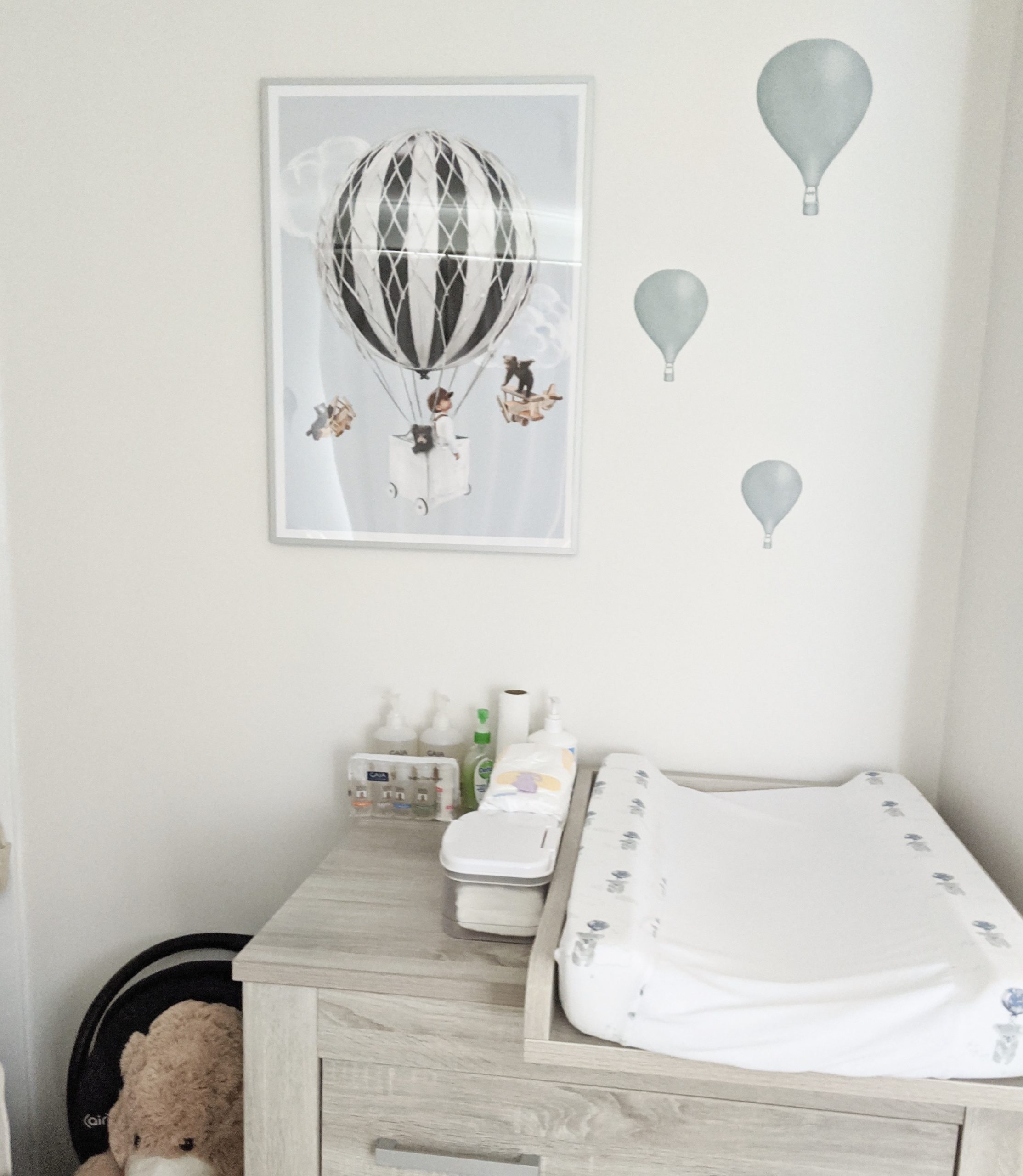 Changing table and changing mat on top with nursery wall print and light blue balloon wall stickers above it