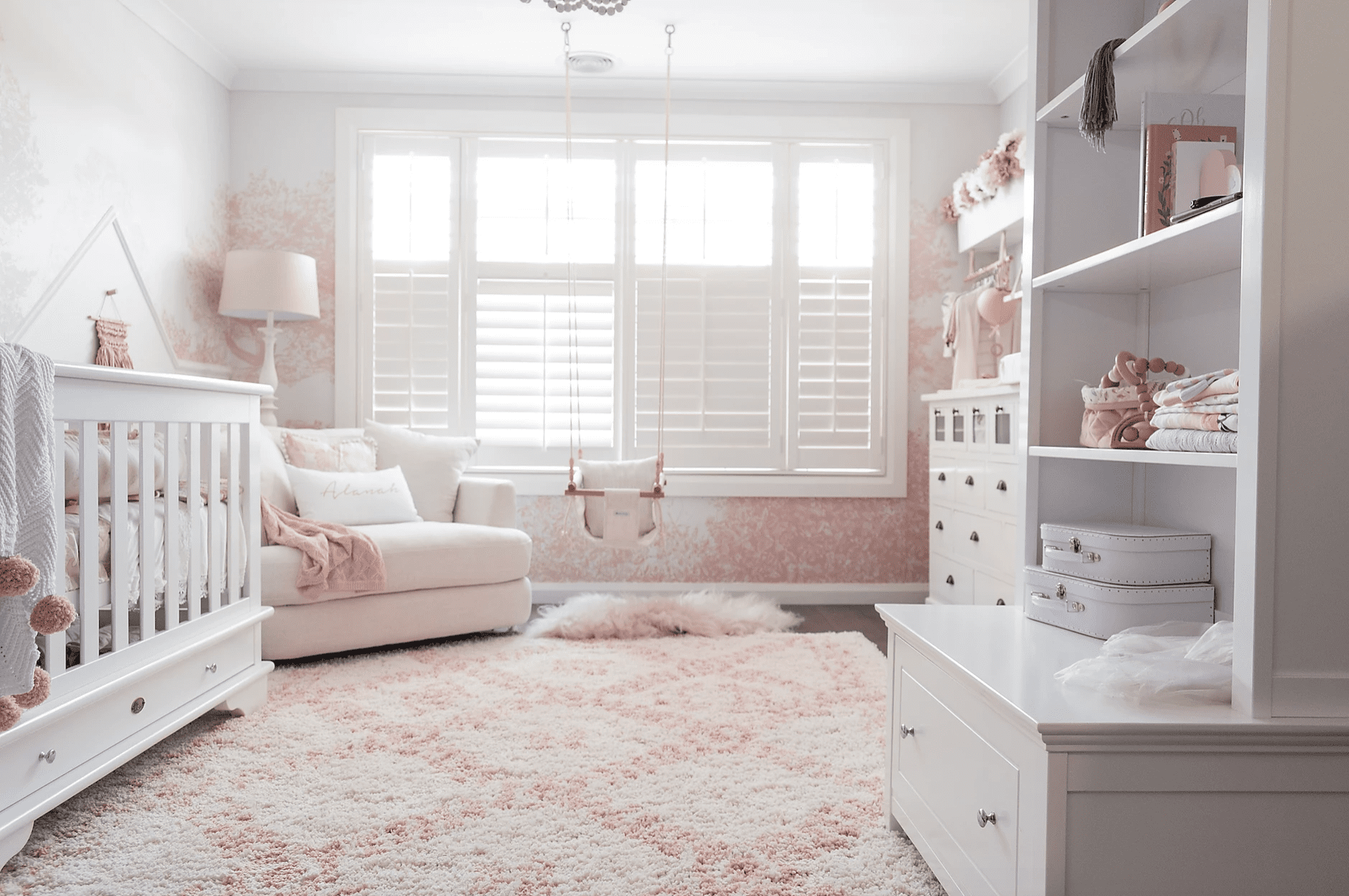 Pink and white nursery room with cot and shelving